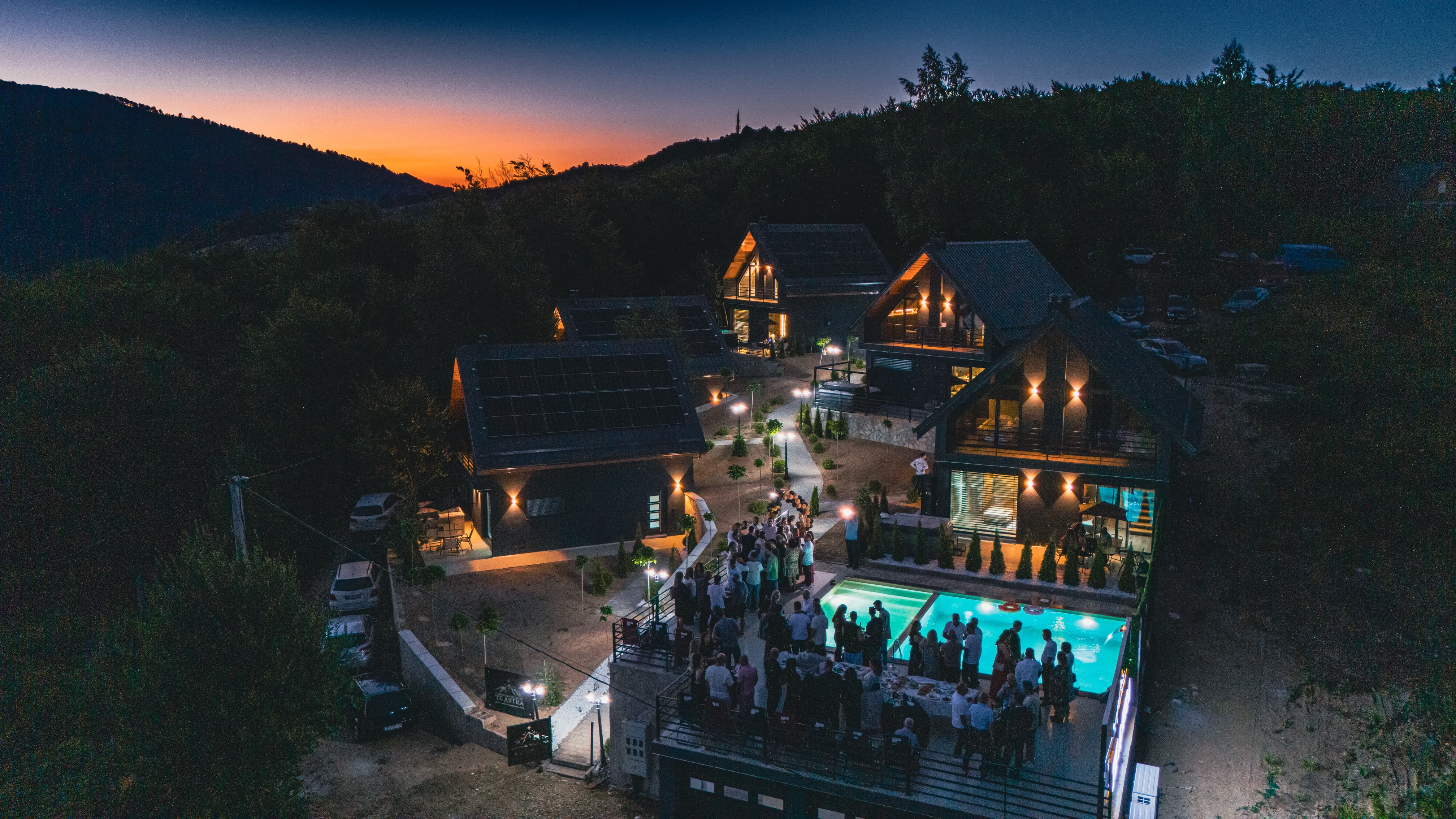Te Astra at dusk — illuminated villas and pool beneath the mountain sunset
